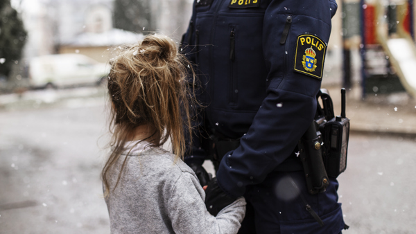 Ett litet barn håller en polis i händerna.