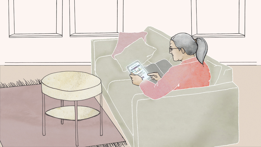 Kvinna sitter i en soffa med en läsplatta.